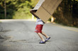© Erickson Stock - A small boy struggles to remove the box off his body while walking on the road.