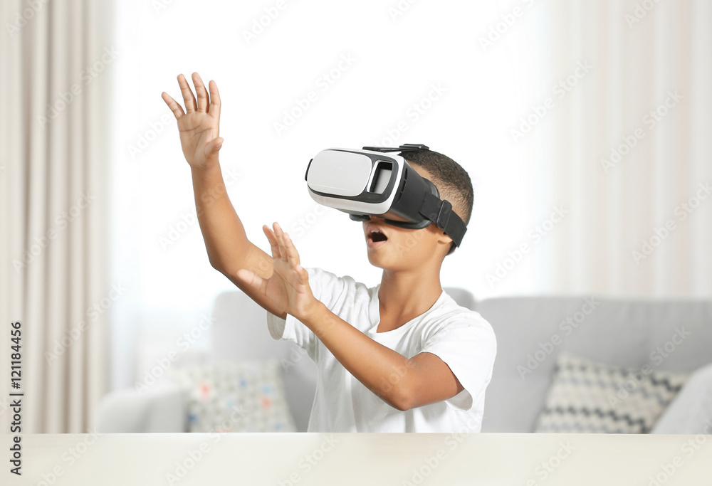 African-American boy wearing virtual reality glasses and sitting at a table
