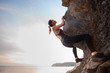 Young female rock climber climbing challenging route on overhanging cliff