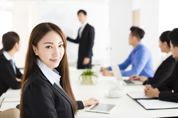 Smiling businesswoman looking at camera with  colleague