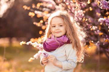 Wall Mural - Smiling kid girl 4-5 year old holding flower wearing casual clothes outdoors. Looking at camera. Childhood.