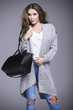 © dorriss - Beautiful young woman in a gray sweater and a black handbag