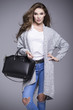 © dorriss - Beautiful young woman in a gray sweater and a black handbag
