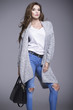 © dorriss - Beautiful young woman in a gray sweater and a black handbag
