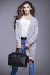 © dorriss - Beautiful young woman in a gray sweater and a black handbag