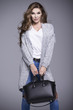 Beautiful young woman in a gray sweater and a black handbag
