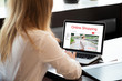 © fizkes - Young woman working on laptop computer, shopping using online web service. Attractive female browsing shopping website. Rear view. Focus on screen. Shopping on-line, fashion concept