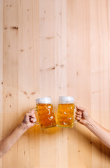 Wall Mural - Two unrecognizable men clinking with beer mugs, studio shot