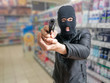 © vchalup - Robbery in store. Robber is aiming and threatening with gun in shop.