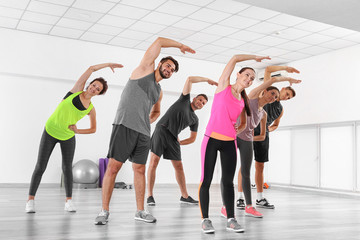 Wall Mural - Group of people practicing yoga in a gym