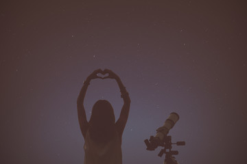 Wall Mural - girl making a heart-shape for the stars with telescope beside her.
