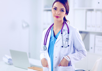 Wall Mural - Portrait of young woman doctor with white coat standing in hospital