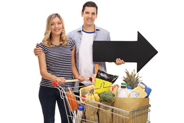 Poster - Couple posing with a shopping cart and an arrow