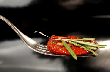 Wall Mural - Slice of dried tomato on fork on black background