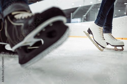 Fototapeta na szkło Man's hockey and women' figure skates on ice empty skating rink