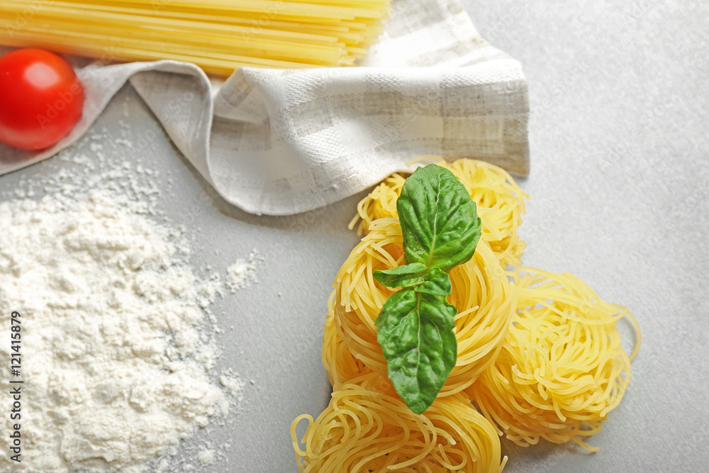 Dry pasta nests with basil on table
