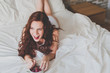 © MIGUEL CANAVATE/ADDICTIVE STOCK - Red-haired woman eating grape on bed