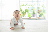 Fototapeta  - Little pretty baby girl crawling on the floor at home