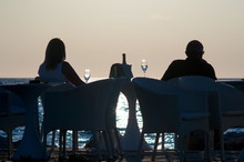 Man And Woman Enjoying Sunset Next To The Sea