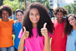 Latin woman with long curly hair showing thumbs up with friends