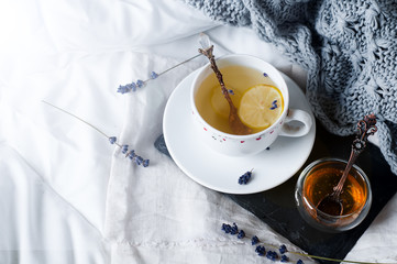 Wall Mural - tray with honey and a cup of hot tea in the bed