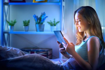 Beauty girl using tablet pc in her bed at night