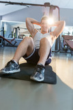 Fototapeta  - Male fitness model doing sit ups and crunches exercising abdomin