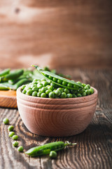 Wall Mural - Green peas in wooden bowl on  rural background