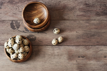 Wooden bowls with quail eggs. Rustic wood background, diffused natural light. A different type of concept image for Easter. Copy space.