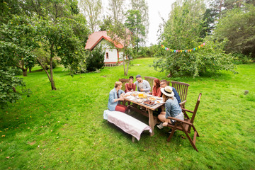 happy friends having dinner at summer garden party