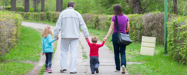 Young family walking in park on beautiful cloudy spring day