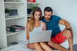 © jakubzak - Young woman and man are sitting on the bed and using laptop pc.