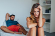 © jakubzak - Young couple is sitting on the bed while woman is thoughtful and