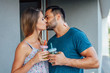 © jakubzak - Young couple are standing at the balcony while kissing and holdi