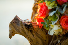 Wedding Rings And Bouquet On Driftwood