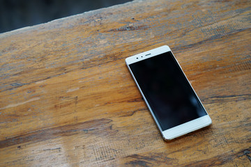 White smart phone with blank screen on wooden table