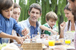 © PhotoAlto - Happy family eating together outdoors at family gathering
