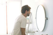 © PhotoAlto - Man looking at self in bathroom mirror