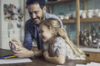 © PhotoAlto - Father and daughter looking at smartphone together