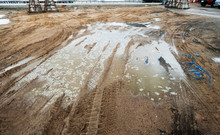 Puddle And Mud With Truck Wheel Track At Construction Site In Rainy Day