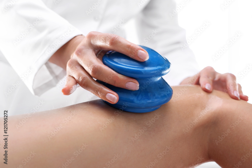 Masaż odchudzający, modelowanie sylwetki. Kosmetyczka masuje uda kobiety gumowymi bańkami do masażu. - obrazy, fototapety, plakaty 