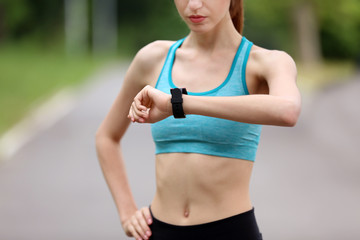 Poster - Young woman checking time after run in park