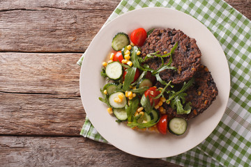 Black bean burger with a salad of fresh vegetables closeup. Horizontal top view
