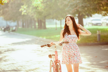 Wall Mural - The young girl with bicycle in park