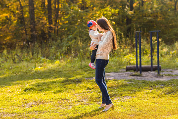 Mother and little daughter playing together in autumn park