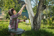 Woman is whitewashing a tree in her own backyard
