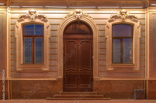 Photographie Deux fenêtres et une porte dans une rangée sur la façade illuminée de nuit de la façade de l'immeuble urbain, Saint-Pétersbourg, en Russie