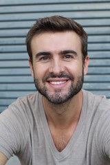 Wall Mural - Portrait of good looking smiling bearded man with perfect white teeth. Young beautiful Caucasian male model with healthy smile posing in studio over gray background