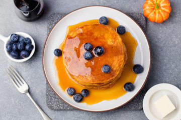 Wall Mural - Pumpkin pancakes with maple syrup and blueberries on a plate Grey stone background Top view