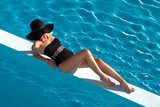 Fototapeta  - Piękna kobieta w eleganckim kostiumie kąpielowym - relaks w basenie